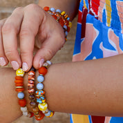 Close-up of a person wearing colorful beaded bracelets on a blurred background