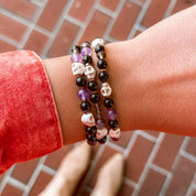 Person wearing a bracelet with beads on a red brick surface