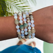 Wrist wearing multiple beaded bracelets with a blurred natural background