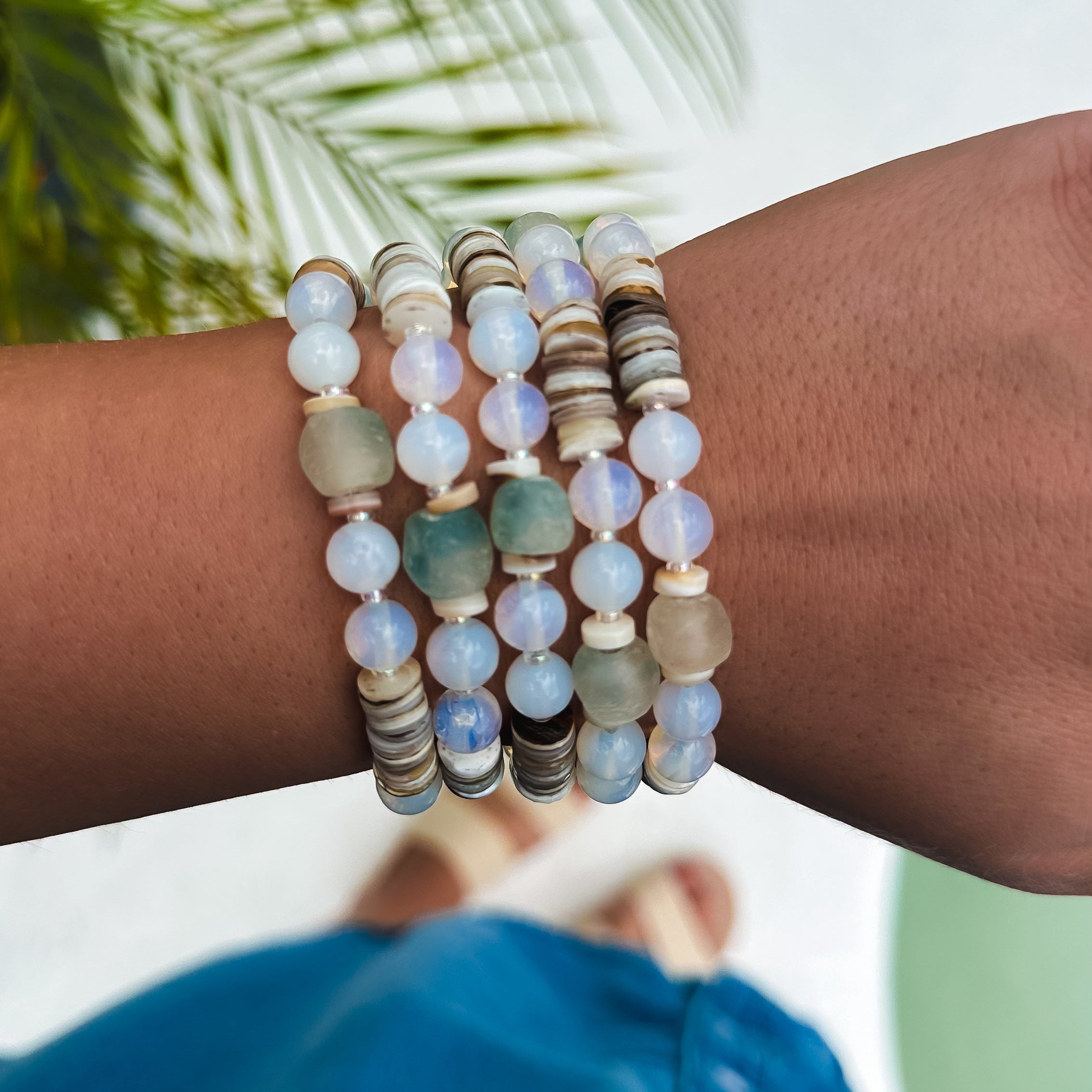 Wrist wearing multiple beaded bracelets with a blurred natural background