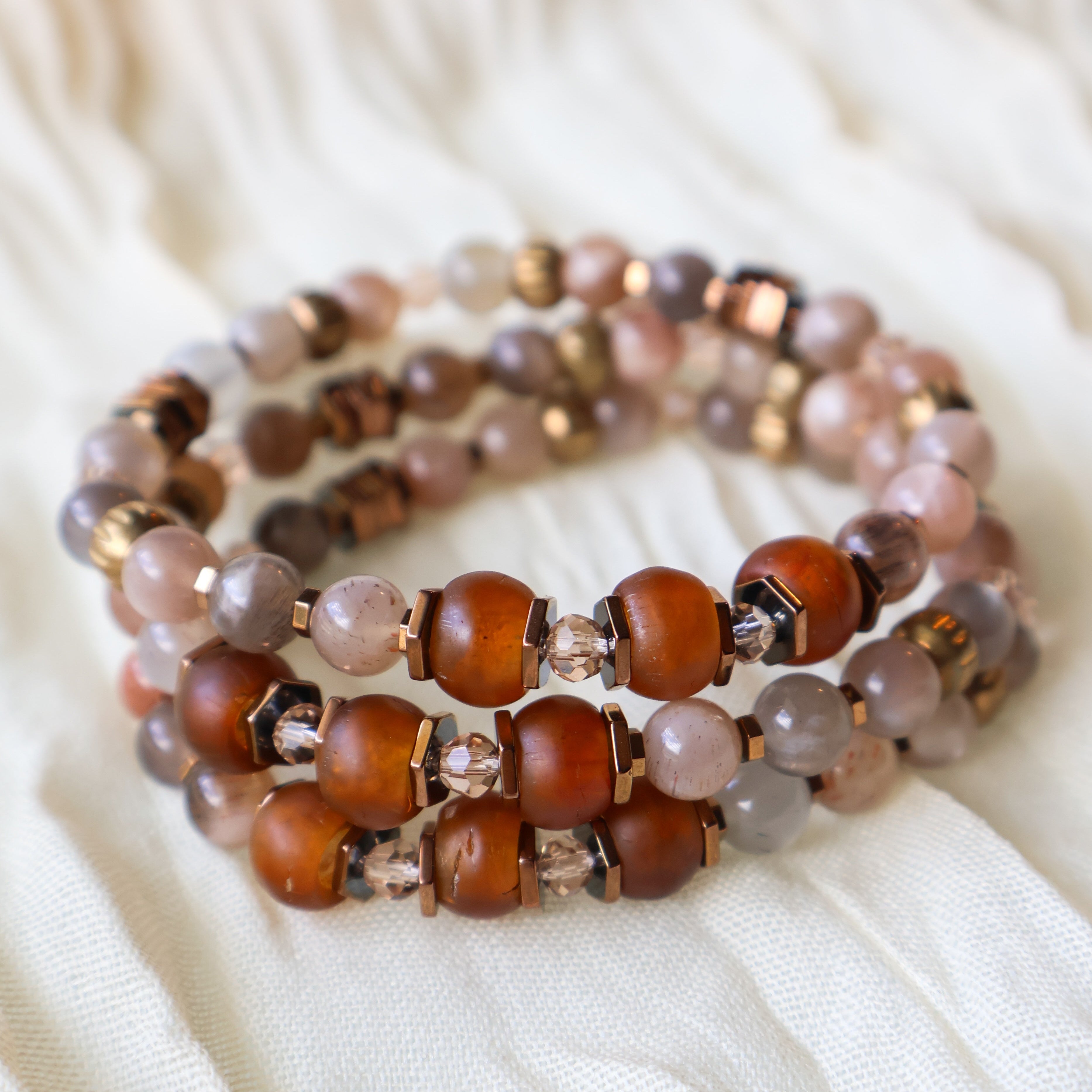 Stack of beaded bracelets on a soft white fabric background