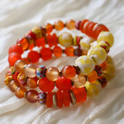 Stack of colorful beaded bracelets on a light fabric background