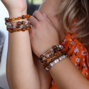 Close-up of a person wearing multiple beaded bracelets on a blurred background