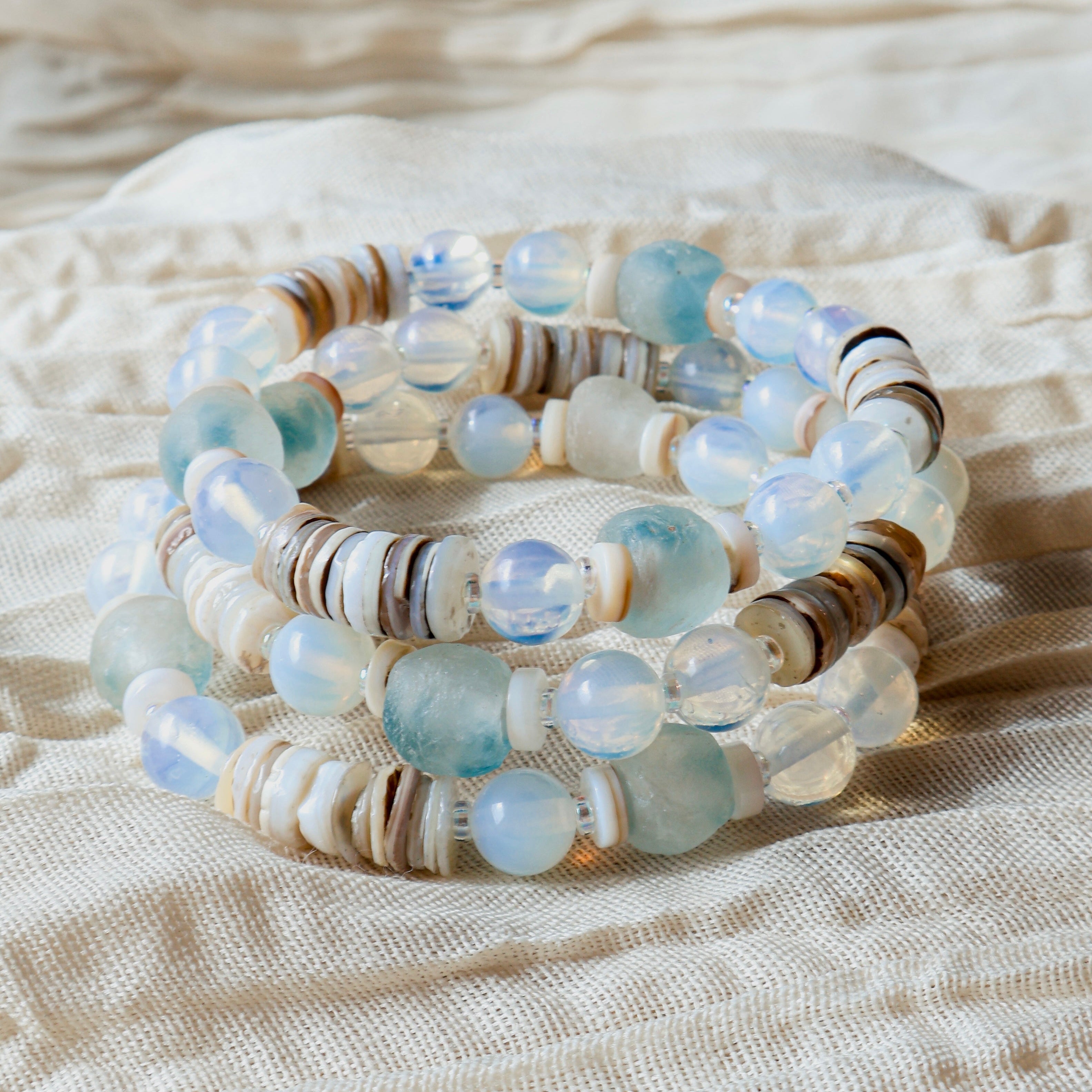 Stack of beaded bracelets on a textured beige fabric background