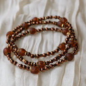 Three brown beaded bracelets on a textured white surface